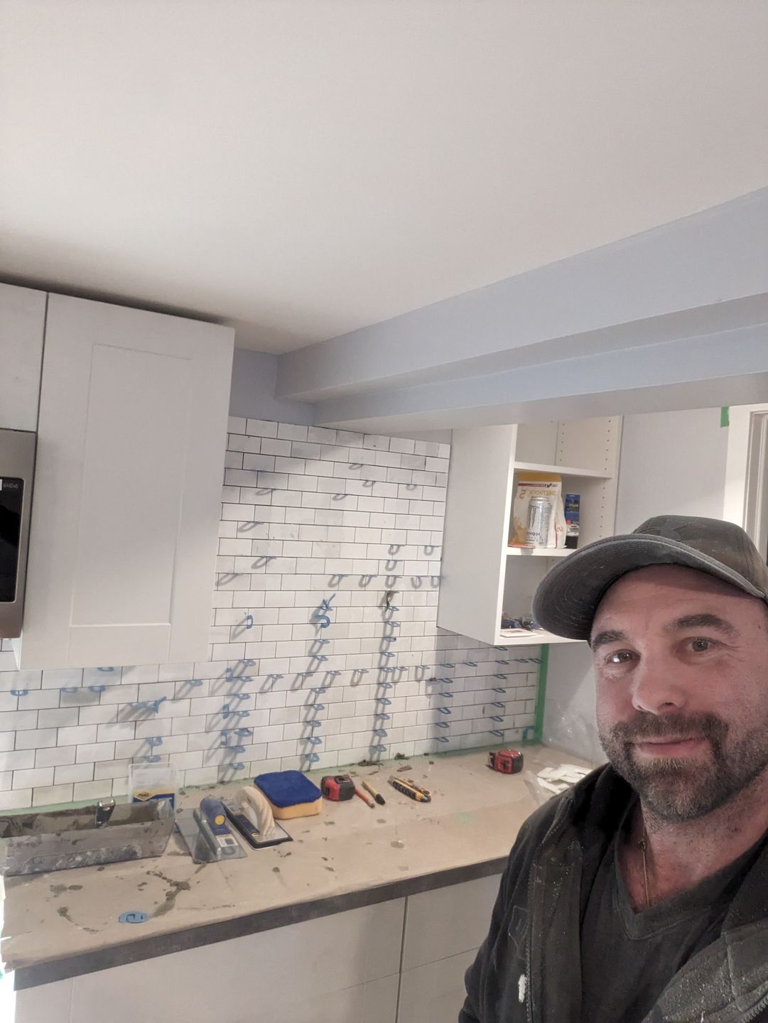 Subway tile backsplash being installed in a basement suite kitchenette, Riverview NB