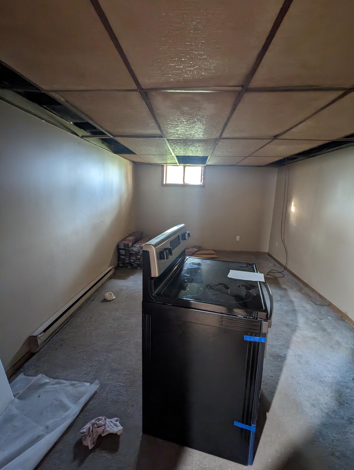 Unfinished basement with dated drop ceiling and bare concrete floor before renovation, Riverview NB