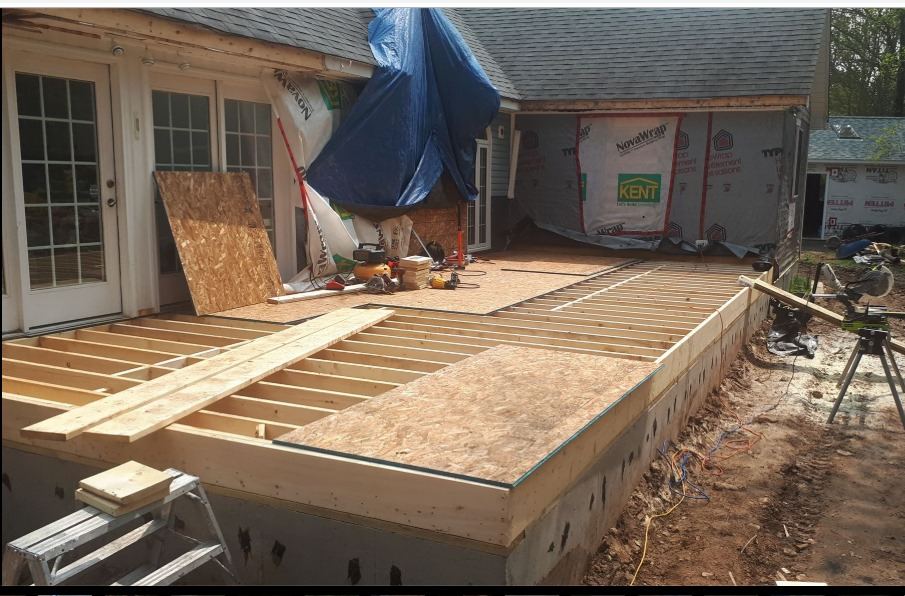 Floor joists and subfloor being installed over a home addition foundation