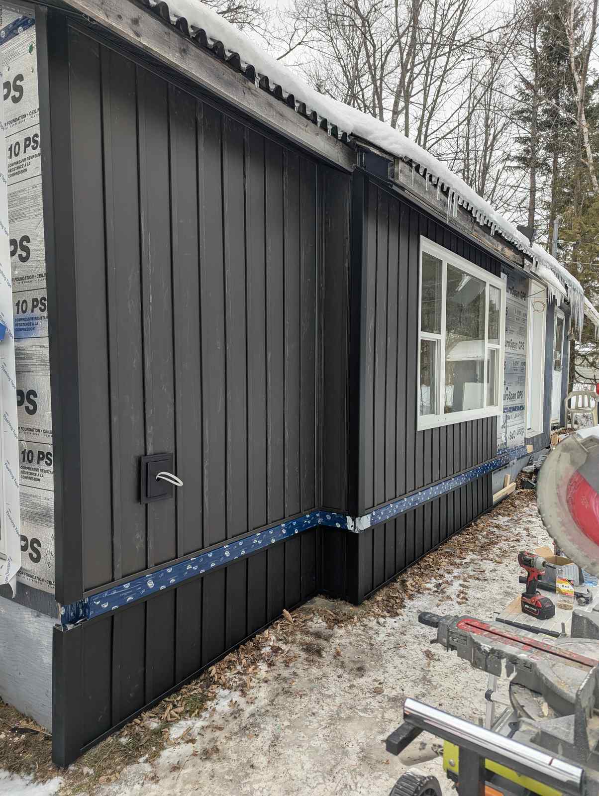 Corner detail and base flashing on black vertical steel siding