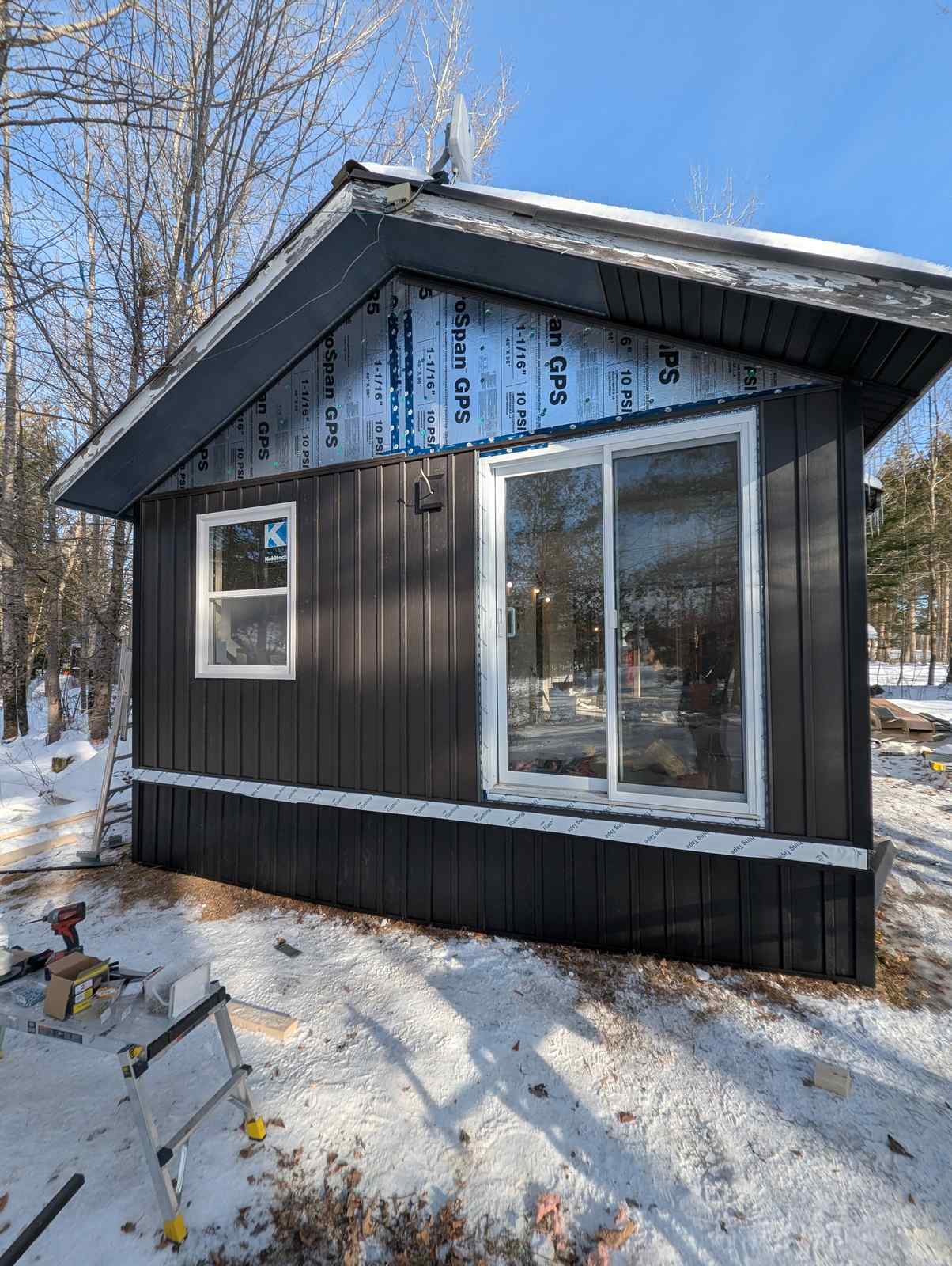 Gable end nearing completion with black vertical siding installed